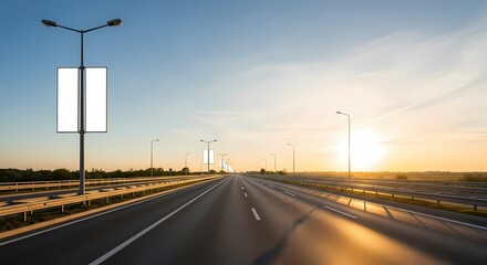 Empty highway stretches towards the horizon under a bright, clear sky during sunset.