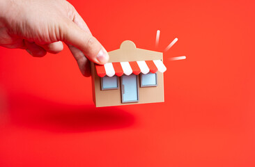 Hand places store on ground. Concept of entrepreneurship, retail opening, and small business...