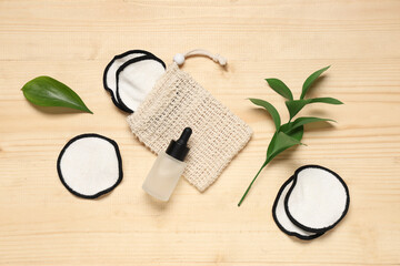 Composition with bag, reusable cotton pads and bottle of cosmetic product on wooden background, closeup