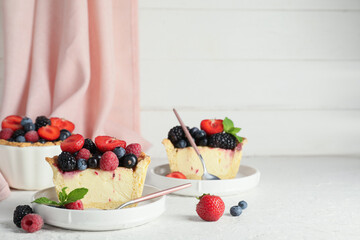 Plates with pieces of delicious berry pie on white grunge background, closeup
