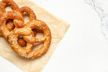 Parchment paper and tasty pretzels on marble background, closeup