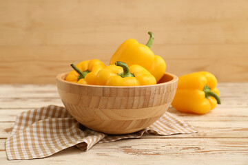 Bowl with yellow bell peppers on white wooden table
