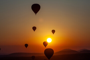 Hot air balloon flying over rocky landscape at sunrise in Cappadocia. Turkey