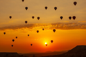 Hot air balloon flying over rocky landscape at sunrise in Cappadocia. Turkey