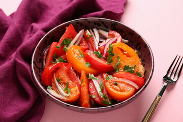 Bowl of fresh tomato salad with red onion and parsley on pink background, closeup