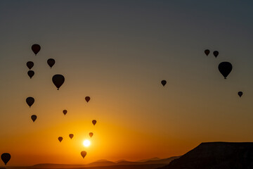 Hot air balloon flying over rocky landscape at sunrise in Cappadocia. Turkey