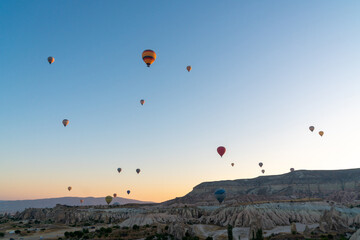 Hot air balloon flying over rocky landscape at sunrise in Cappadocia. Turkey