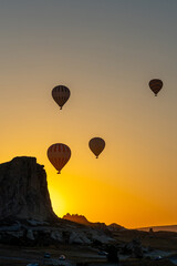 Hot air balloon flying over rocky landscape at sunrise in Cappadocia. Turkey