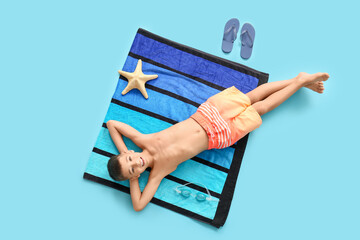 Cute little boy lying on blanket against blue background