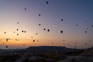 Hot air balloon flying over rocky landscape at sunrise in Cappadocia. Turkey
