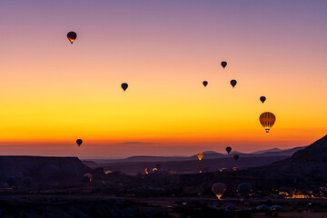Hot air balloon flying over rocky landscape at sunrise in Cappadocia. Turkey