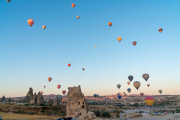 Hot air balloon flying over rocky landscape at sunrise in Cappadocia. Turkey