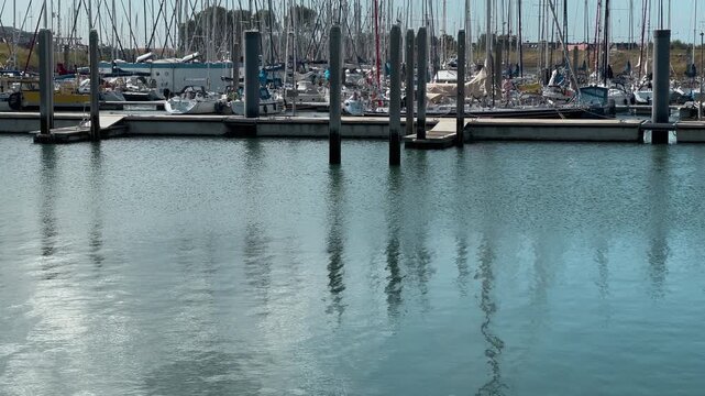 Marina with sailing boats and yachts moored at wooden docks on calm water in netherlands harbor
