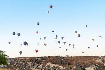 Hot air balloon flying over rocky landscape at sunrise in Cappadocia. Turkey