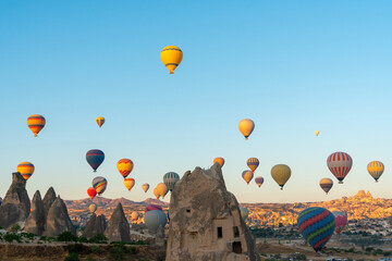 Hot air balloon flying over rocky landscape at sunrise in Cappadocia. Turkey