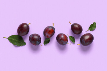 Fresh ripe plums and leaves on lilac background