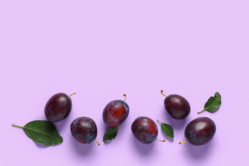 Fresh ripe plums and leaves on lilac background