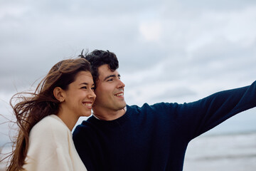 Young couple enjoying a sunny beach day, capturing joyful selfies and creating lasting memories during their romantic vacation together