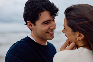 Fototapeta premium Happy couple sharing a tender moment on the beach, enjoying each other's company and the beautiful scenery