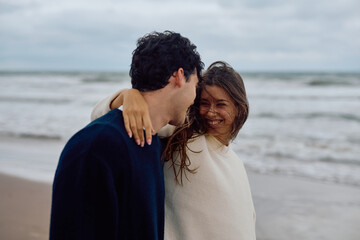 Happy couple embracing on the beach, savoring their romantic getaway while enjoying the gentle...