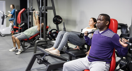 African-american man training on shoulder press machine in gym