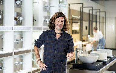 Portrait of handsome man making choice in a plumbing and building materials store