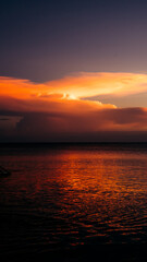 Fototapeta premium Beautiful sunset creating an aesthetically view in a combination of red, yellow, orange colors and patterns overlooking the ocean, peaceful and calm