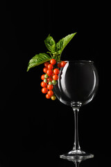 Cherry Tomatoes Overflowing in Wine Glass with Basil on Black Background