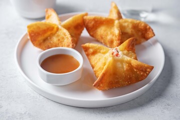 Crab rangoon with sauce in a plate
