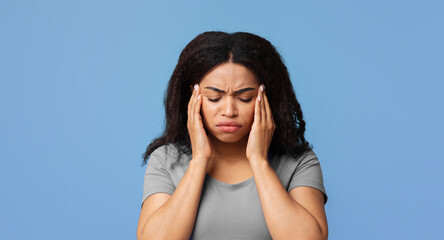Headache and migraine concept. African american lady suffering from hypertension over blue studio...