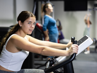 Obraz premium Caucasian woman training on exercise bike in gym
