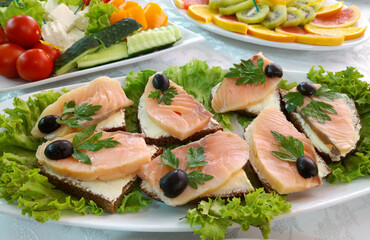 sandwiches with red fish for a snack on the buffet table. decorated with olives, lettuce leaves and sprigs of herbs. delicious snack or appetizer