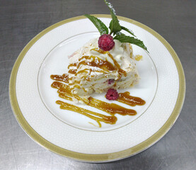 meringue roll with raspberries and caramel. delicious dessert with fresh berries, poured with caramel topping, garnished with a sprig of fresh mint