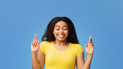 Cherished wish. African american lady crossing fingers and smiling, begging for luck, praying for...