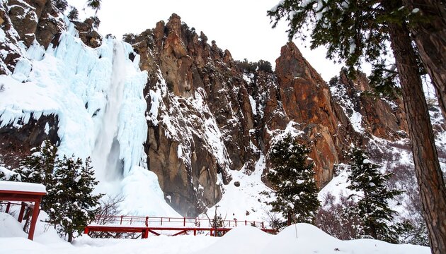 Frozen waterfall cascades down snow-covered rocks in winter scenery