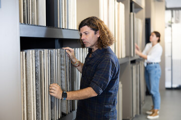 Confident male customer picking out wall tile materials for bathroom in hardware store
