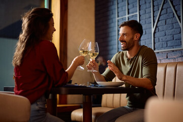Happy couple toasting while drinking wine and eating in a restaurant.