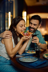 Young woman enjoying in pizza during lunch with her boyfriend.