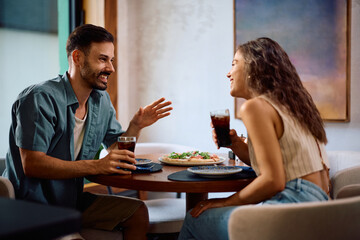 Happy couple talking while having lunch in pizzeria.