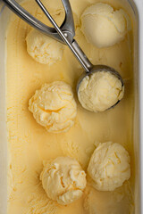 Vanilla ice cream scoops in tray with scoop utensil, close-up food background