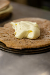 Spreading cream on cake layer, close-up view of dessert preparation in bakery kitchen