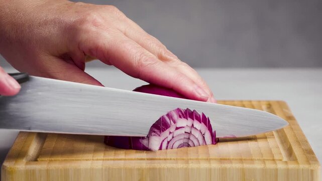 chef cut onion on cutting board with sharp knife for making healthy meal and cooking, cook cutting red juicy onions for making salad, food closeup in kitchen