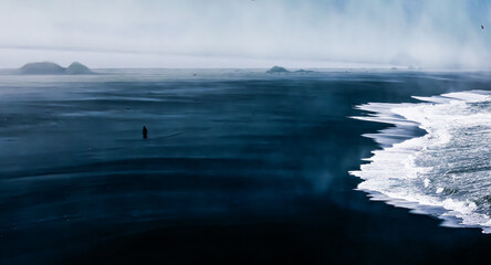silhouette of a person walking on the black sand beach in southern Iceland