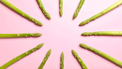 Fresh asparagus spears arranged in a circle on a pink background