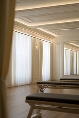 Bright and minimalistic Pilates reformer studio interior with soft natural light, neutral tones, wooden floors and modern fitness equipment creating a calm and elegant wellness atmosphere