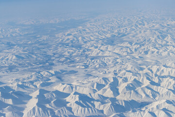 Aerial view of snow-capped mountains. Winter snowy mountain landscape. Air travel to the far North of Russia. Khal-Urekchen ridge, Kolyma Mountains, Magadan Region, Siberia, Russian Far East.