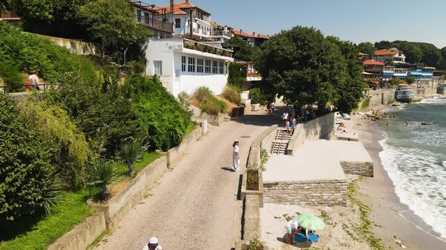 Woman walking in old city of Nessebar near city in Bulgaria. Drone view from above. Summer holidays destination
