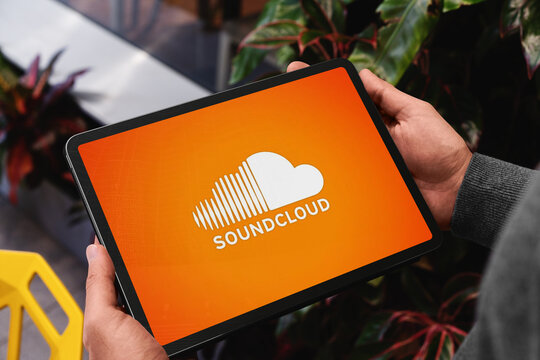 Man holding tablet showing soundcloud logo on orange screen