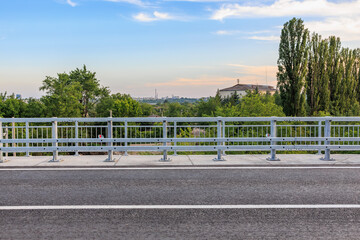 Naklejka premium Concrete road bridge with steel railings and lush greenery under blue sky