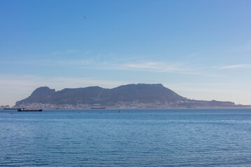 Gibraltar coast with rocky shore and cargo ship. Gibraltar, spain. september 2025.